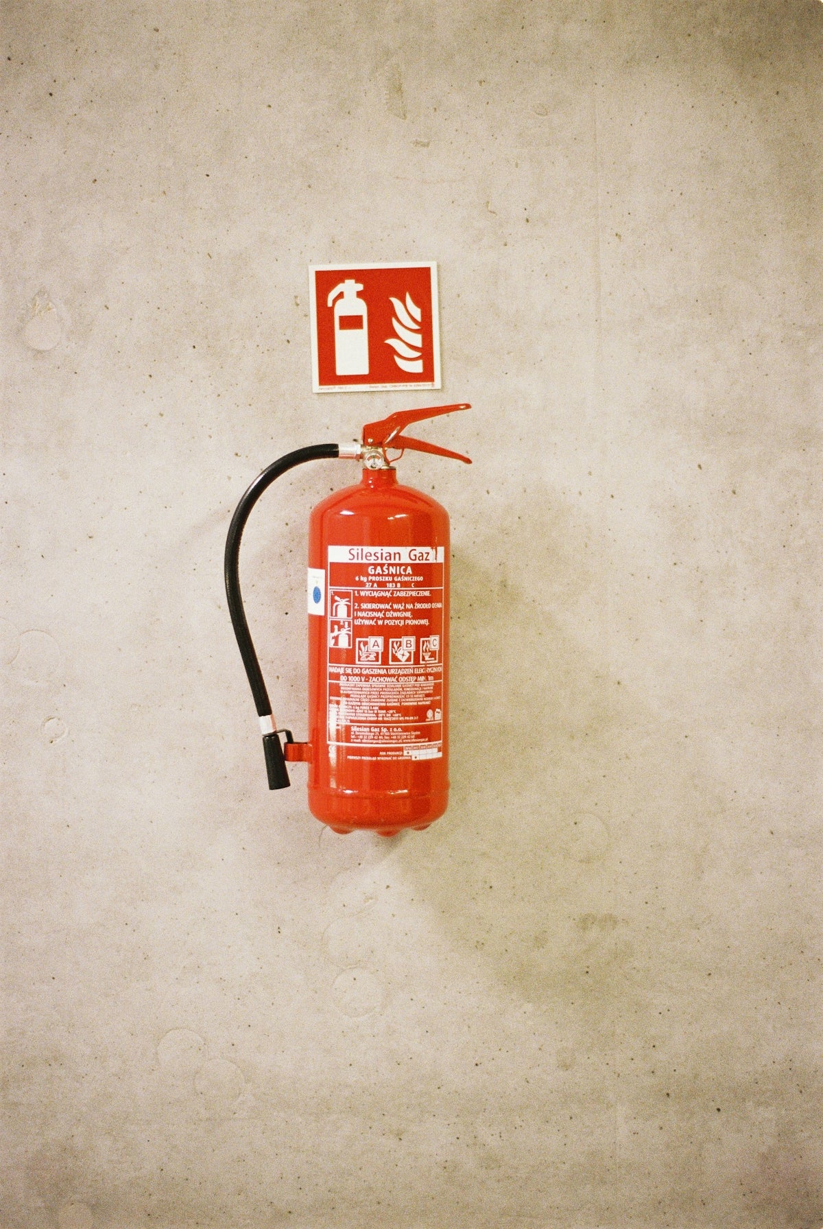 Red fire extinguisher mounted on a concrete wall.