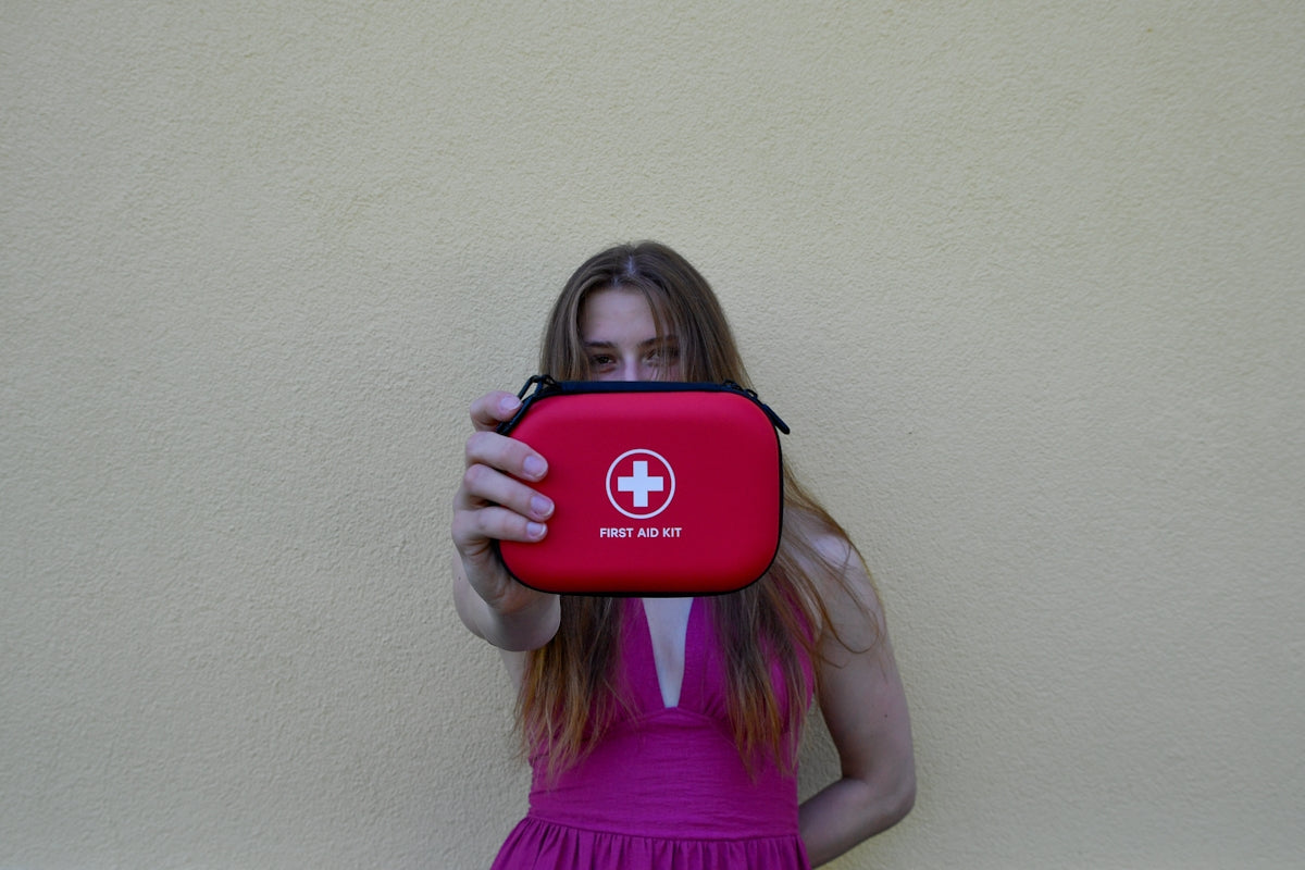 Woman holding a red first aid kit.
