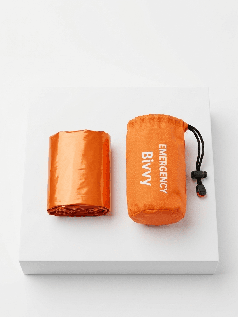 Orange emergency bivy sack with packaging on a white background