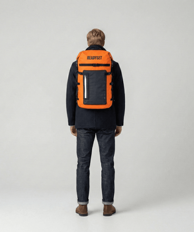 Person with orange ReadySet Solo Set emergency backpack on a plain background